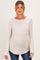 woman wearing a light beige long sleeve maternity top with a curved hem and visible baby bump