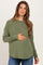 woman wearing a green long sleeve maternity top and holding her baby bump