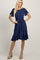 blonde woman wearing a navy blue short sleeve ruffle hem dress with a waist tie and tan heels