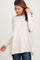 smiling pregnant woman wearing a cream long sleeve maternity tunic sweater and dark jeans