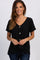 woman wearing a black short sleeve button down top with a front tie knot and blue jeans