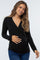 woman wearing a black long sleeve maternity top and holding her baby bump