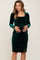 woman wearing a dark green velvet long sleeve maternity dress with a square neckline and side slit, holding her baby bump