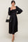 woman wearing a black smocked midi dress with puff sleeves and holding a black handbag