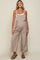 woman wearing a light brown maternity jumpsuit with wide legs and buttons, showcasing her baby bump.
