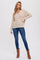 woman wearing a beige chunky knit sweater with button details and blue skinny jeans, paired with brown ankle boots