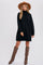 woman wearing a black turtleneck sweater dress with long sleeves and brown knee-high boots, styled with a wide-brimmed hat
