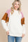 woman wearing a cream colored fuzzy pullover sweatshirt with pink and brown color-block sleeves