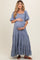 woman wearing a light blue maternity maxi dress with puff sleeves and lace detailing, holding her baby bump