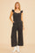 woman wearing a black denim jumpsuit with ruffle straps and wide legs paired with white boots