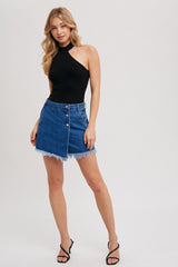 woman wearing a black one-shoulder bodysuit and a denim mini skirt with frayed hem and button details