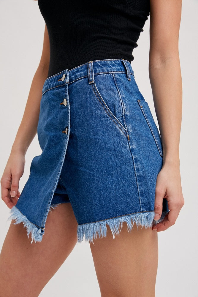 woman wearing a dark blue denim skirt with frayed hem and button details on the front