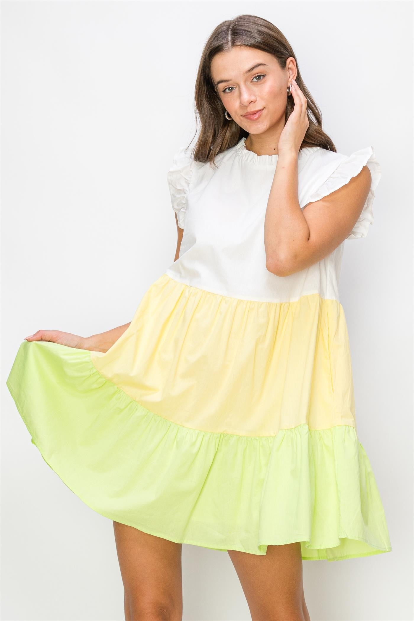 woman wearing a color-blocked short sleeve ruffle hem dress in white, yellow, and lime green