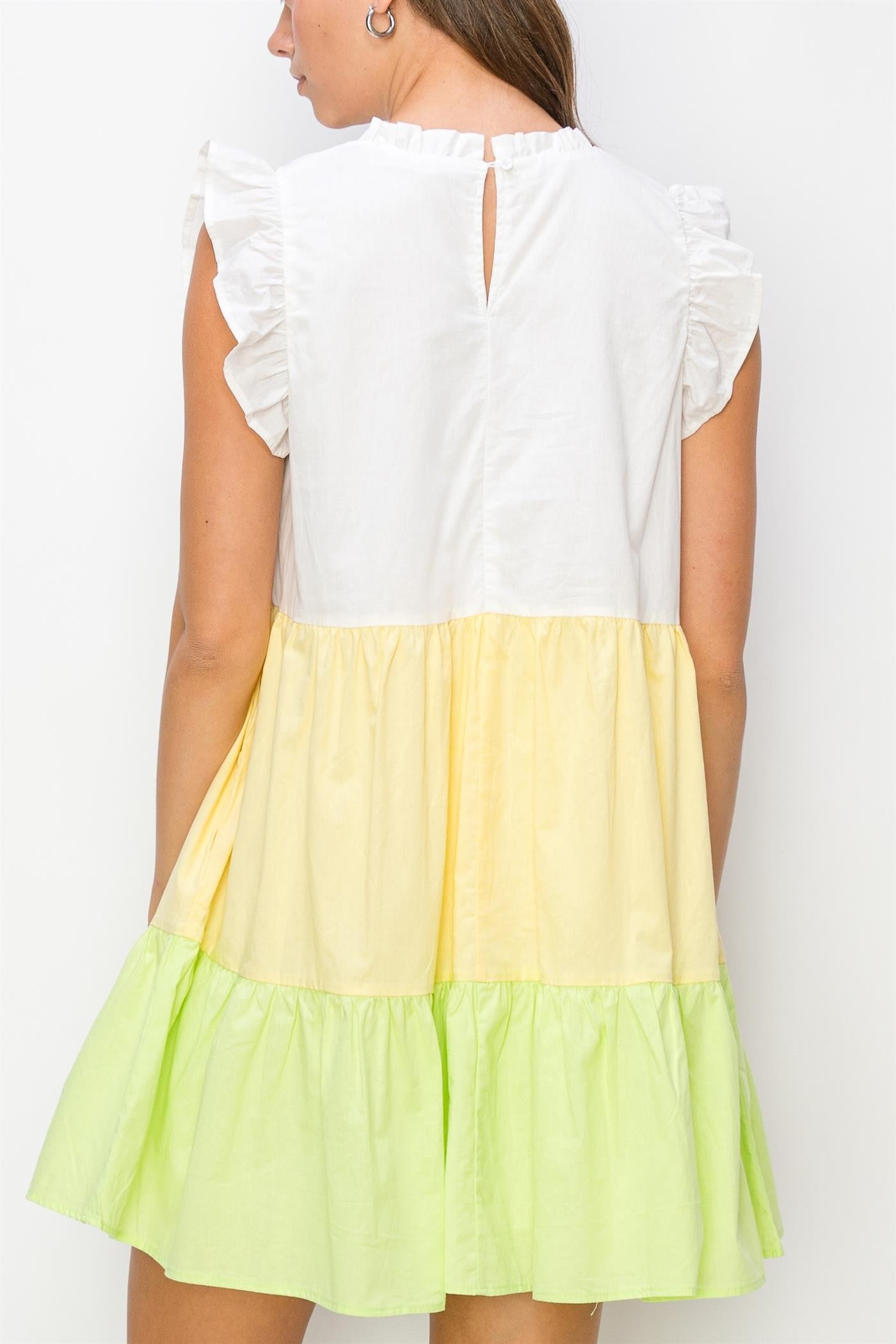 woman wearing a white, yellow, and green color-block tiered dress with ruffled sleeves and a keyhole back
