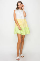 woman wearing a color-blocked sleeveless dress with white, yellow, and green tiers, styled with ruffled sleeves and sandals
