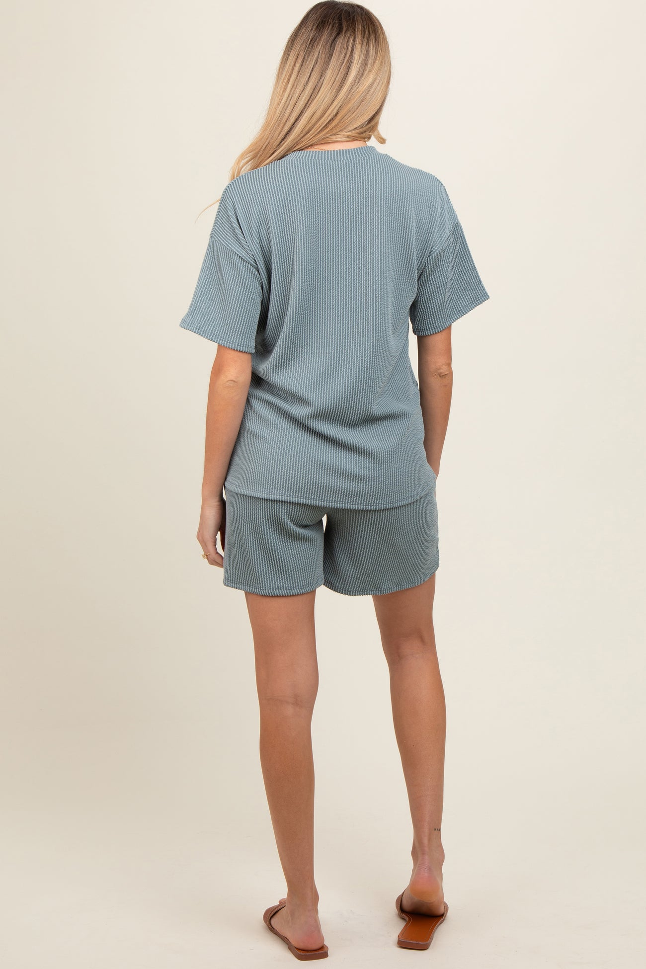 woman wearing a teal ribbed maternity loungewear set, featuring a short sleeve top and matching shorts