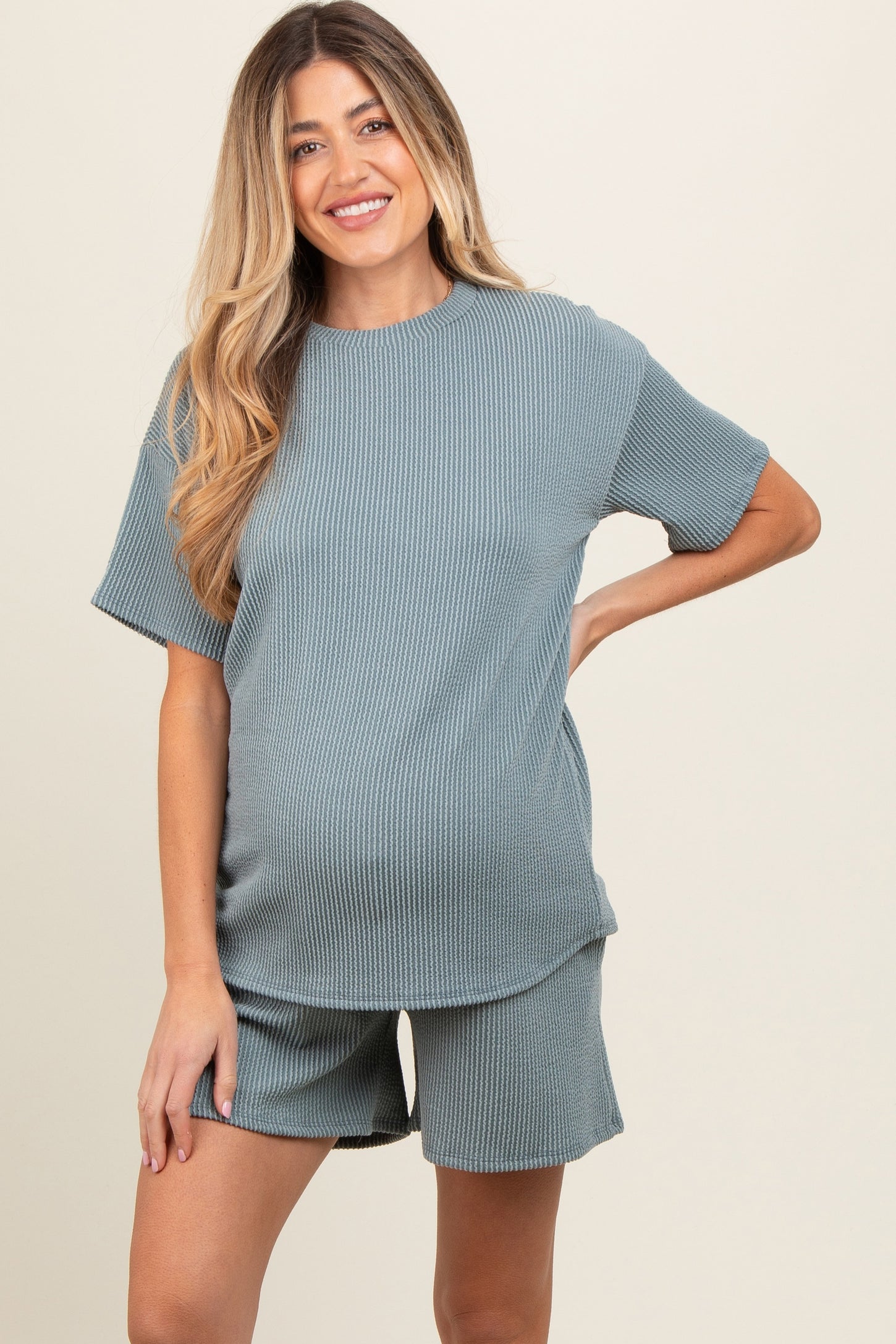 woman wearing a cozy ribbed maternity set in teal with a loose top and shorts, showcasing her baby bump