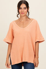 woman wearing a peach-colored loose-fitting top with ruffled sleeves and a v-neckline