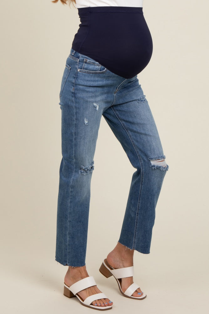 woman wearing distressed light blue maternity jeans with a navy blue over-the-bump panel and a visible baby bump