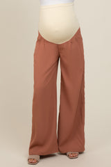 woman wearing rust-colored wide-leg maternity pants with a beige over-the-bump panel