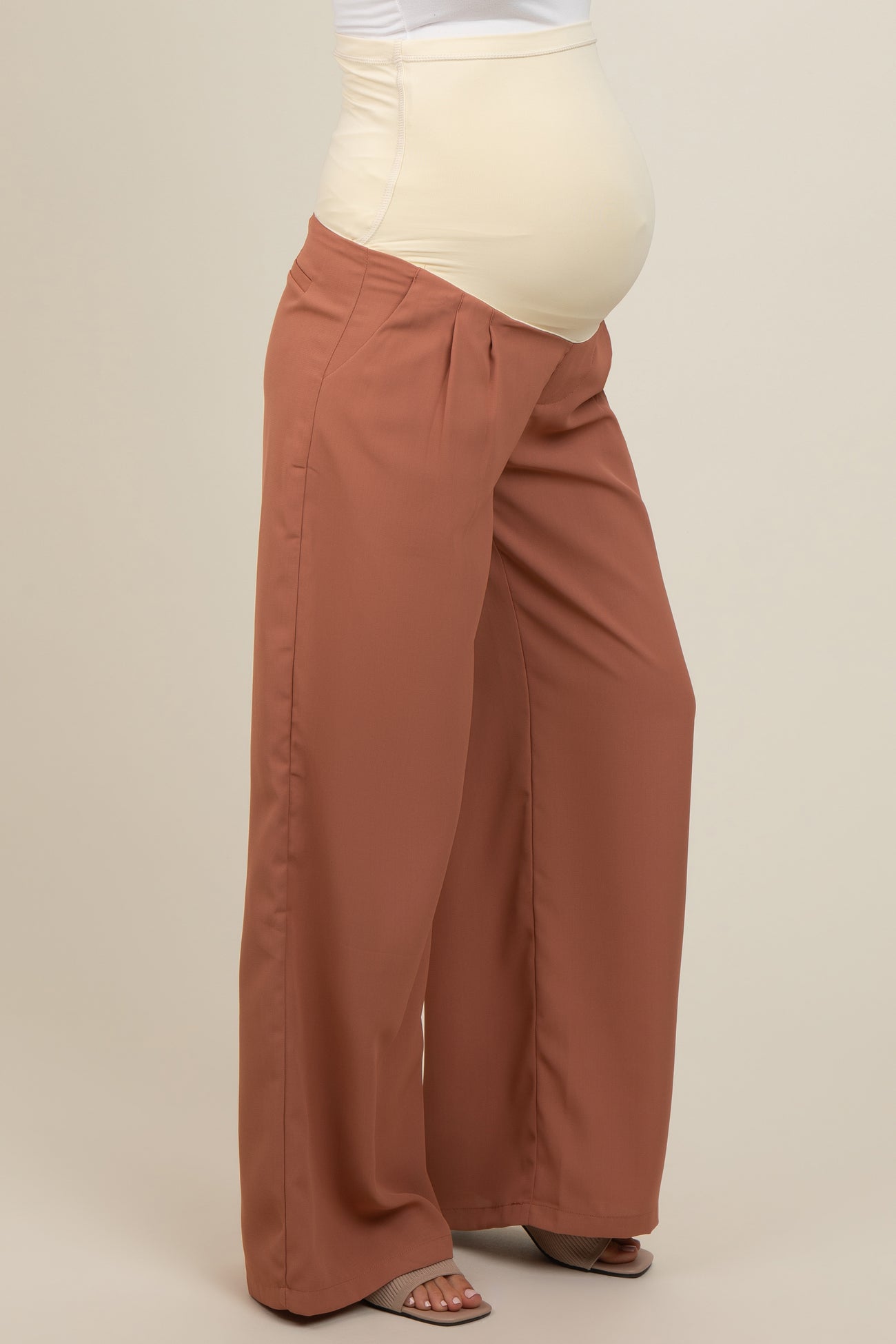 woman wearing rust-colored maternity wide-leg pants with a supportive belly panel and a visible baby bump