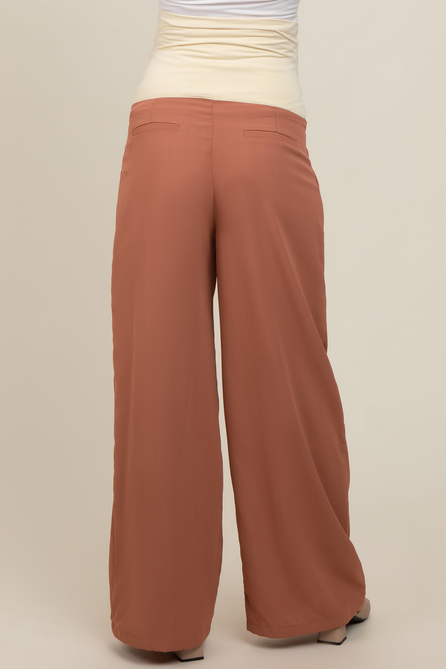 woman wearing rust-colored maternity wide-leg pants, view of the back with vertical seams and pockets