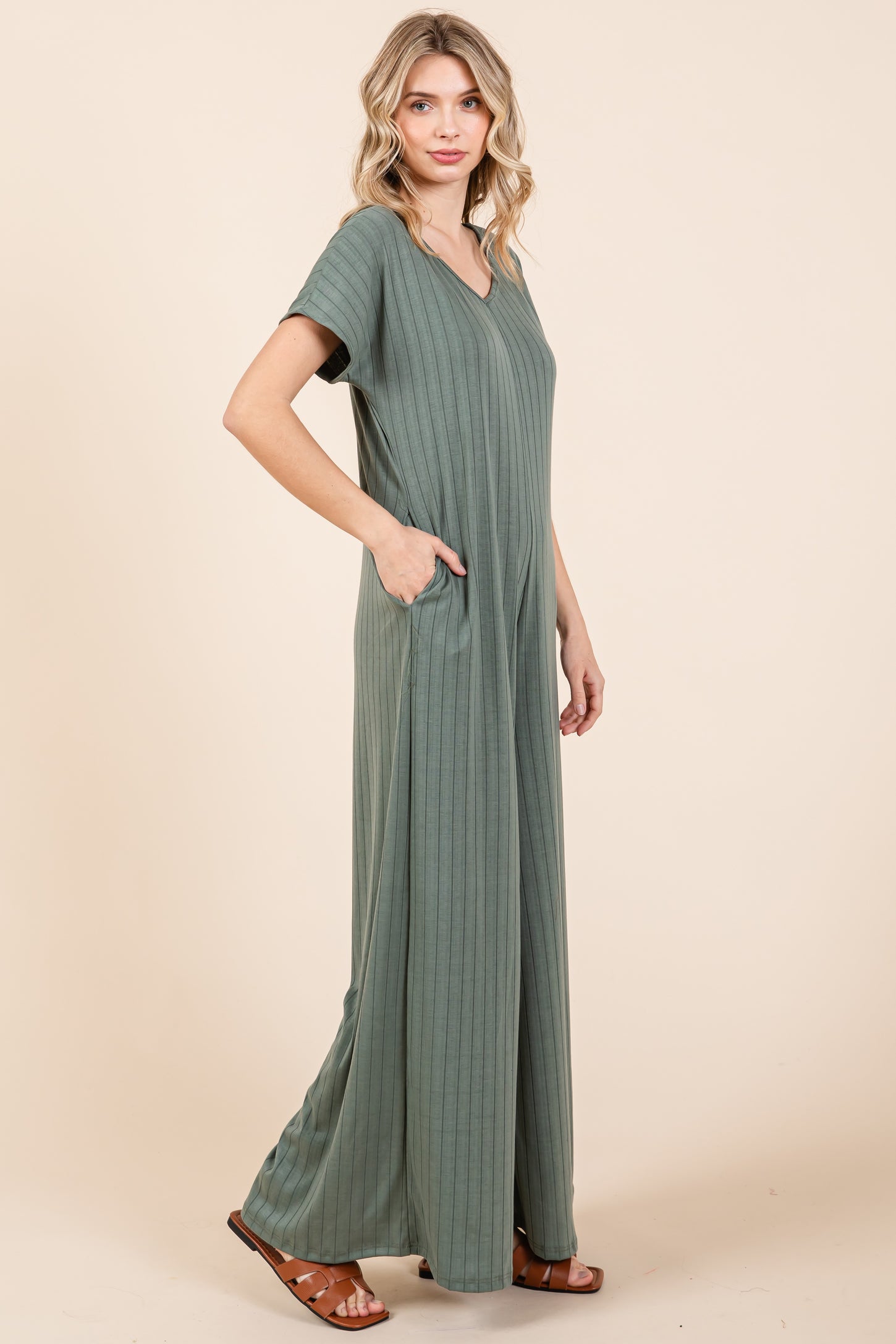 woman wearing a green ribbed maxi dress with a v-neck and pockets, standing in a relaxed pose