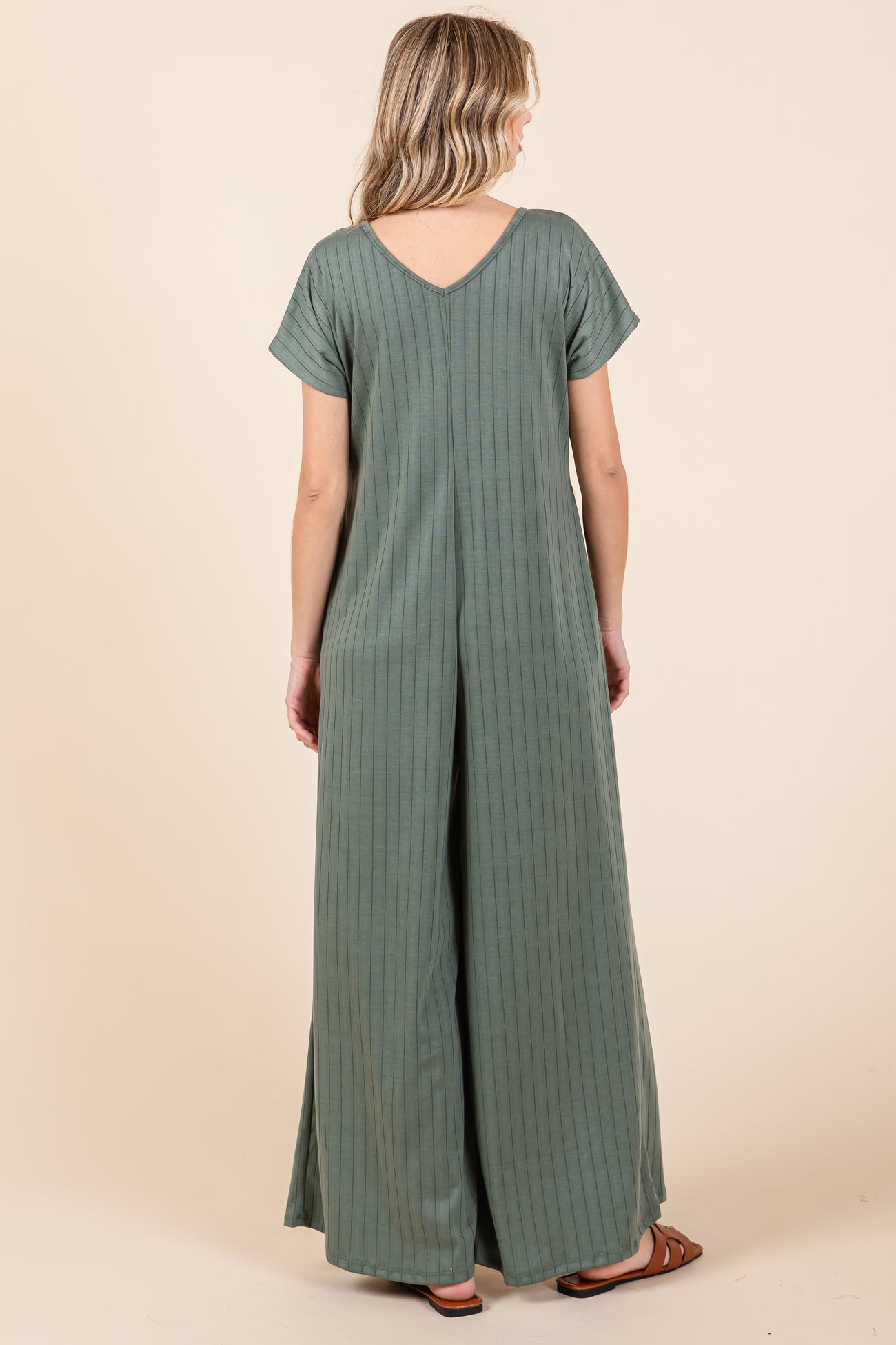 woman wearing a green striped jumpsuit with short sleeves and a v-back design, seen from the back