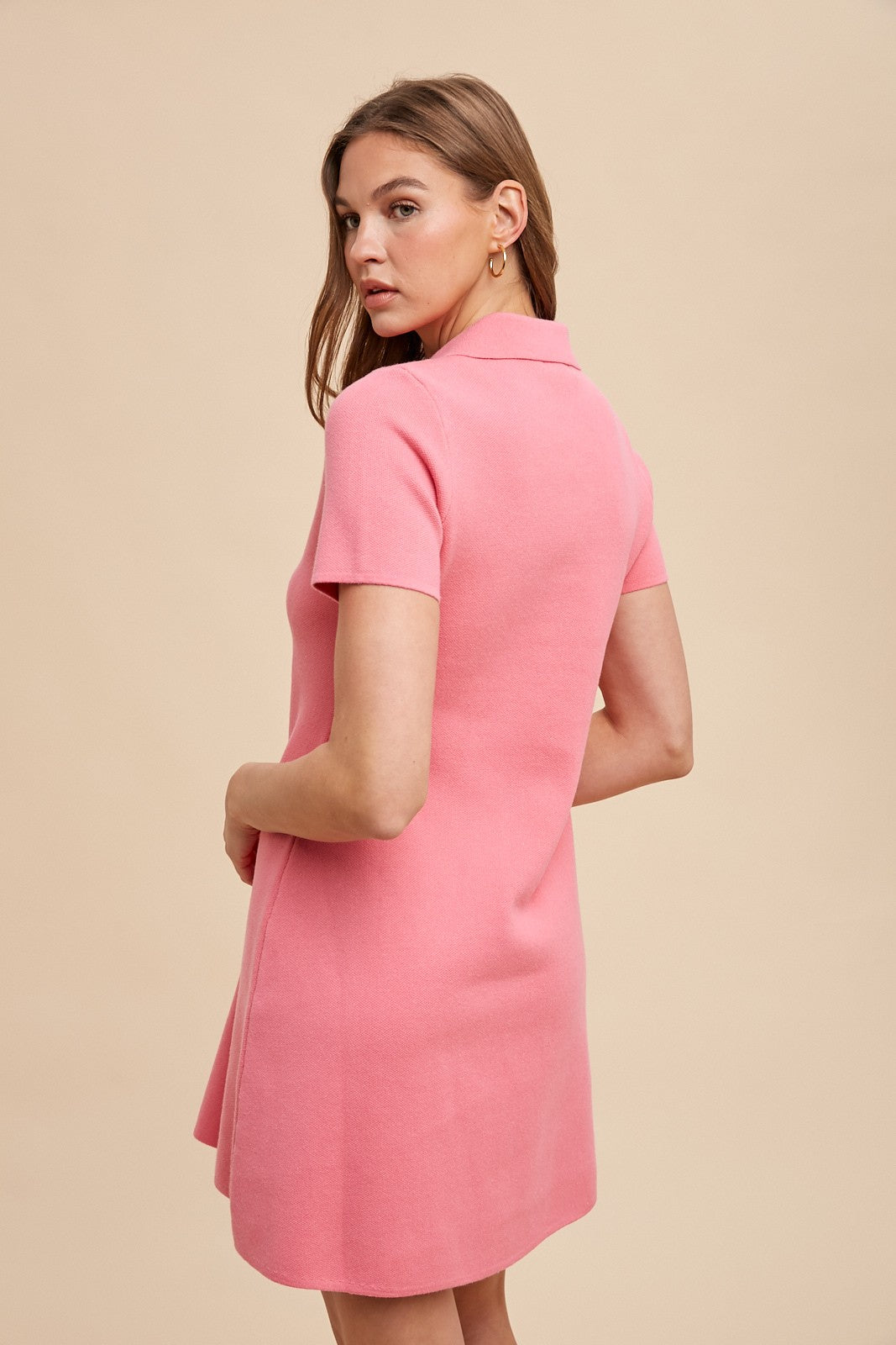 woman wearing a short sleeve pink polo dress, viewed from the back