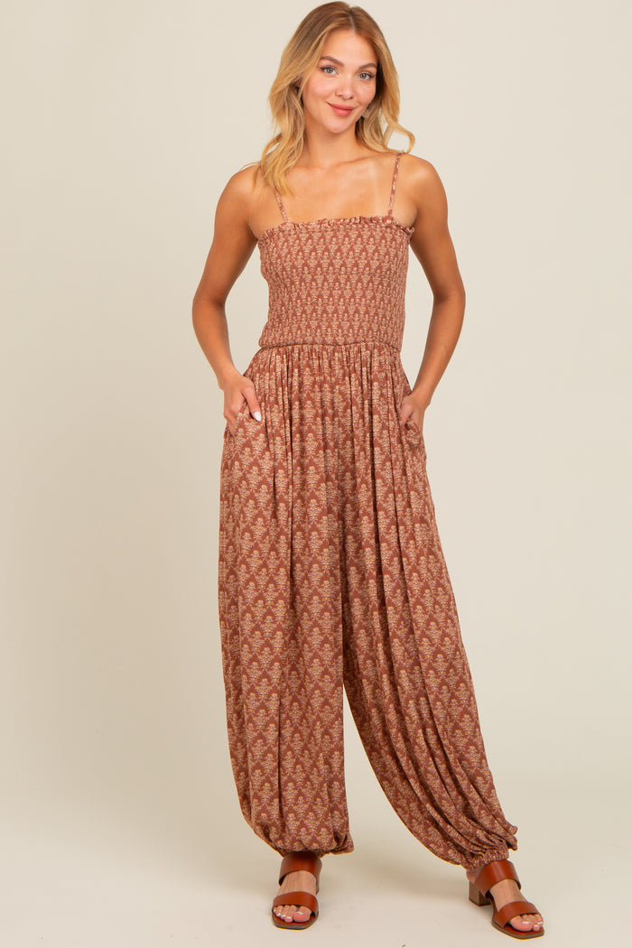 woman wearing a brown patterned jumpsuit with adjustable straps and pockets, styled with brown sandals