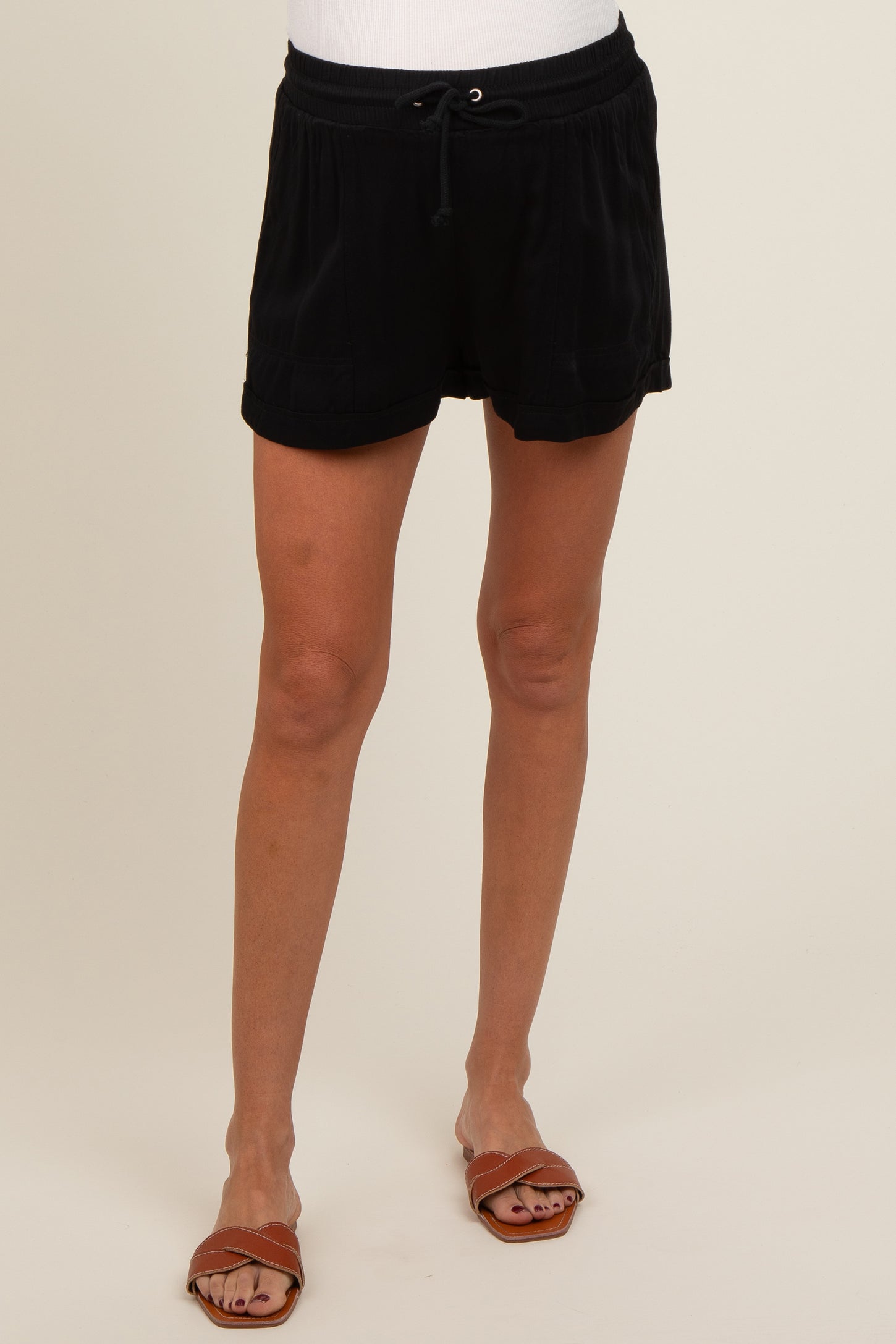 woman wearing black maternity shorts with an adjustable waistband, styled for comfort during pregnancy