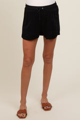 woman wearing black maternity shorts with an adjustable waistband, styled for comfort during pregnancy