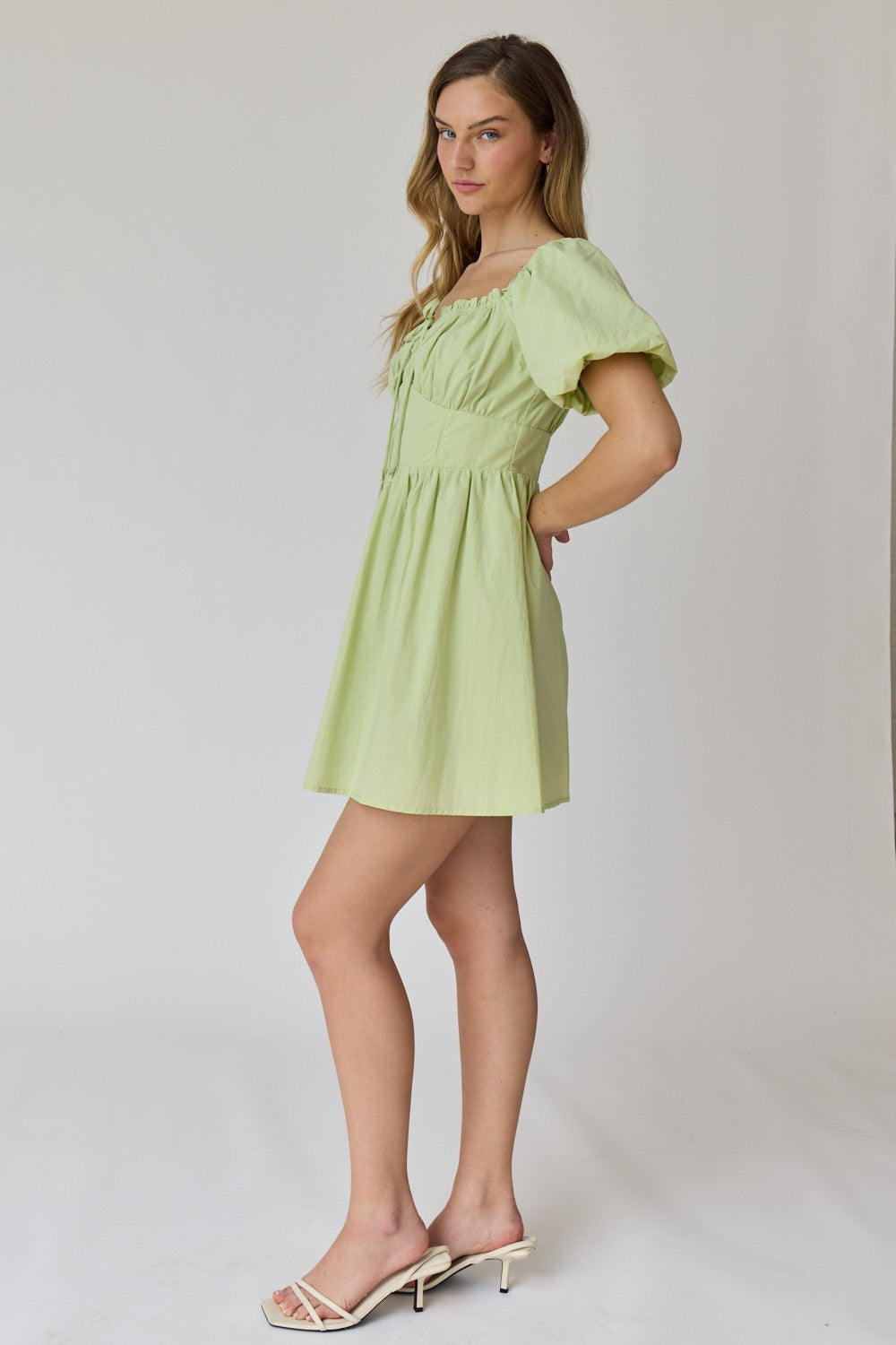 woman wearing a light green puff sleeve mini dress with a fitted bodice and flared skirt