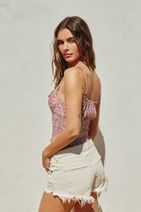 woman wearing a floral-printed pink top with adjustable straps and white distressed shorts