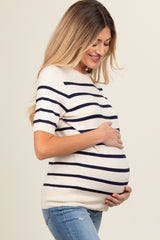 woman wearing a cream and navy striped maternity top and holding her baby bump