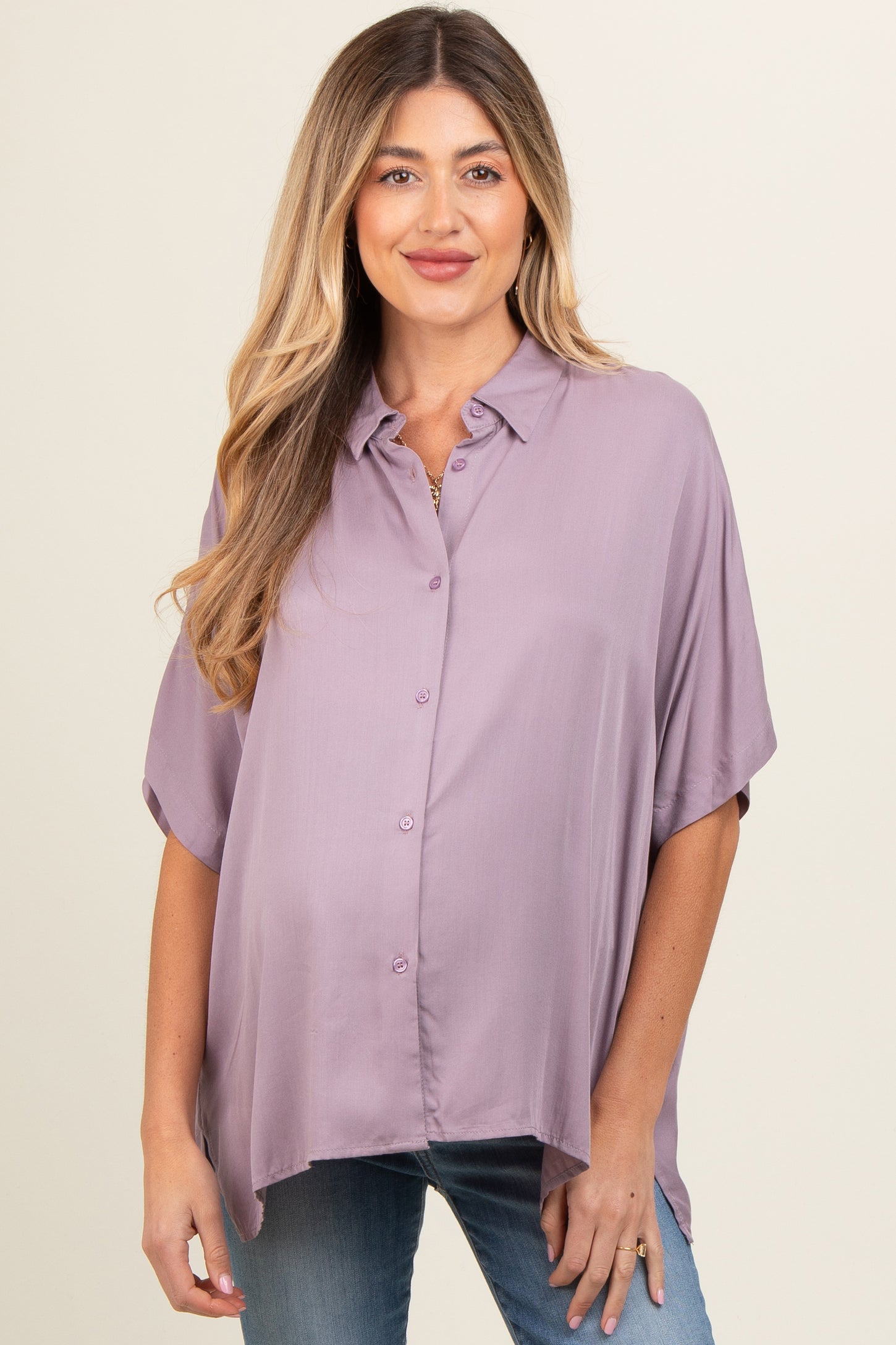 woman wearing a soft lavender short sleeve maternity shirt with button details and a visible baby bump