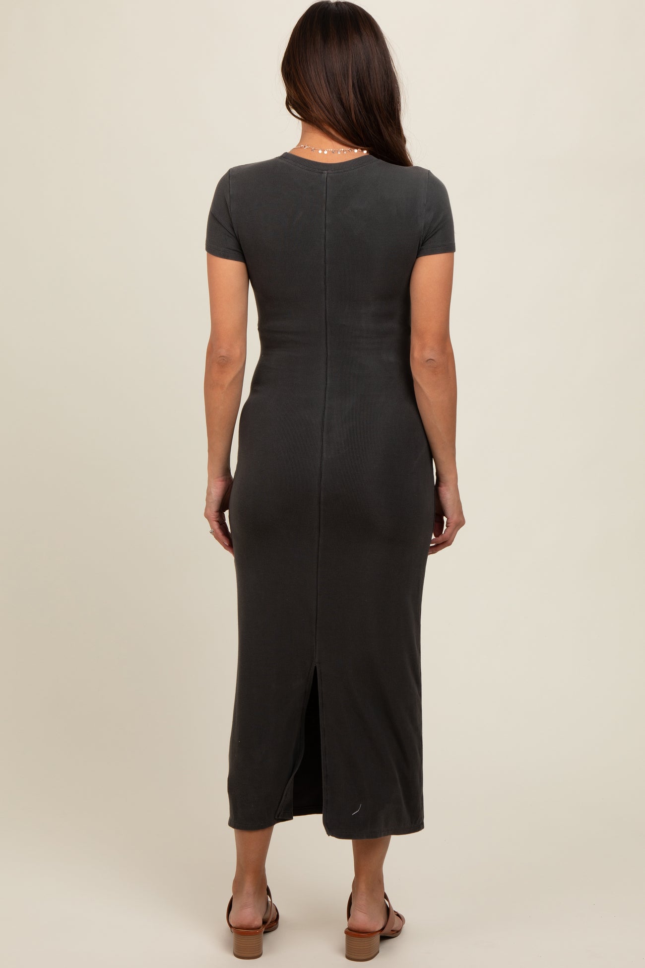 woman wearing a dark gray maternity maxi dress with a back slit and short sleeves, showing a fitted silhouette