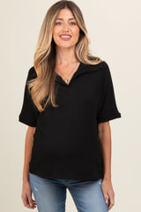 woman wearing a black short sleeve polo maternity top and blue jeans, baby bump is visible