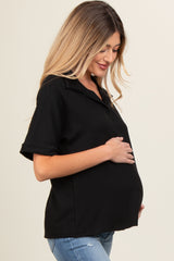woman wearing a black ribbed maternity polo shirt and holding her baby bump