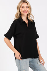 woman wearing a black ribbed polo style top with a collar and short sleeves