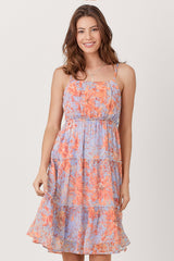 woman wearing a floral print spaghetti strap dress with tiers in shades of blue and orange