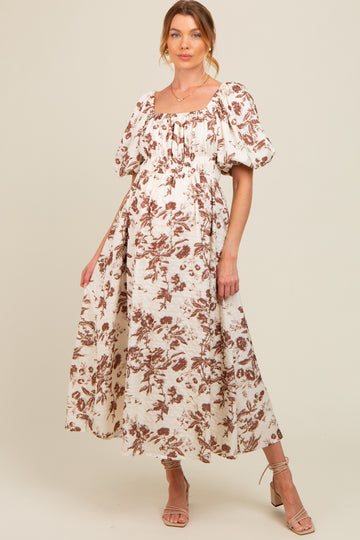 woman wearing a brown and beige floral print maternity maxi dress with puff sleeves and a gathered bodice