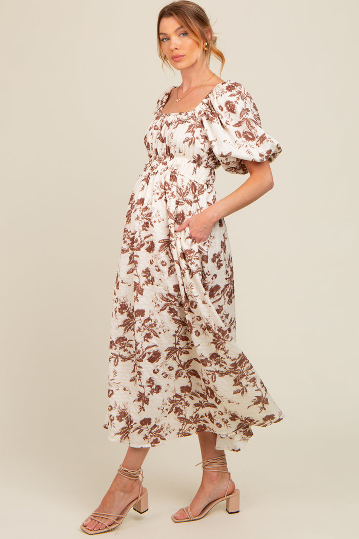 woman wearing a floral print maternity dress with puff sleeves and a flowy skirt, showcasing a baby bump