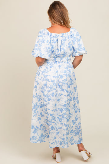 woman wearing a blue and white floral maternity plus maxi dress with puff sleeves and a gathered back detail