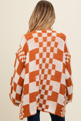 woman wearing an oversized orange and white checkered maternity sweater, showing the back view