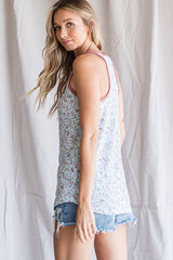 woman wearing a light floral tank top with a pink trim and distressed denim shorts, showing her back