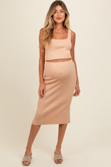woman wearing a nude ribbed maternity crop top and matching midi skirt with a fitted silhouette