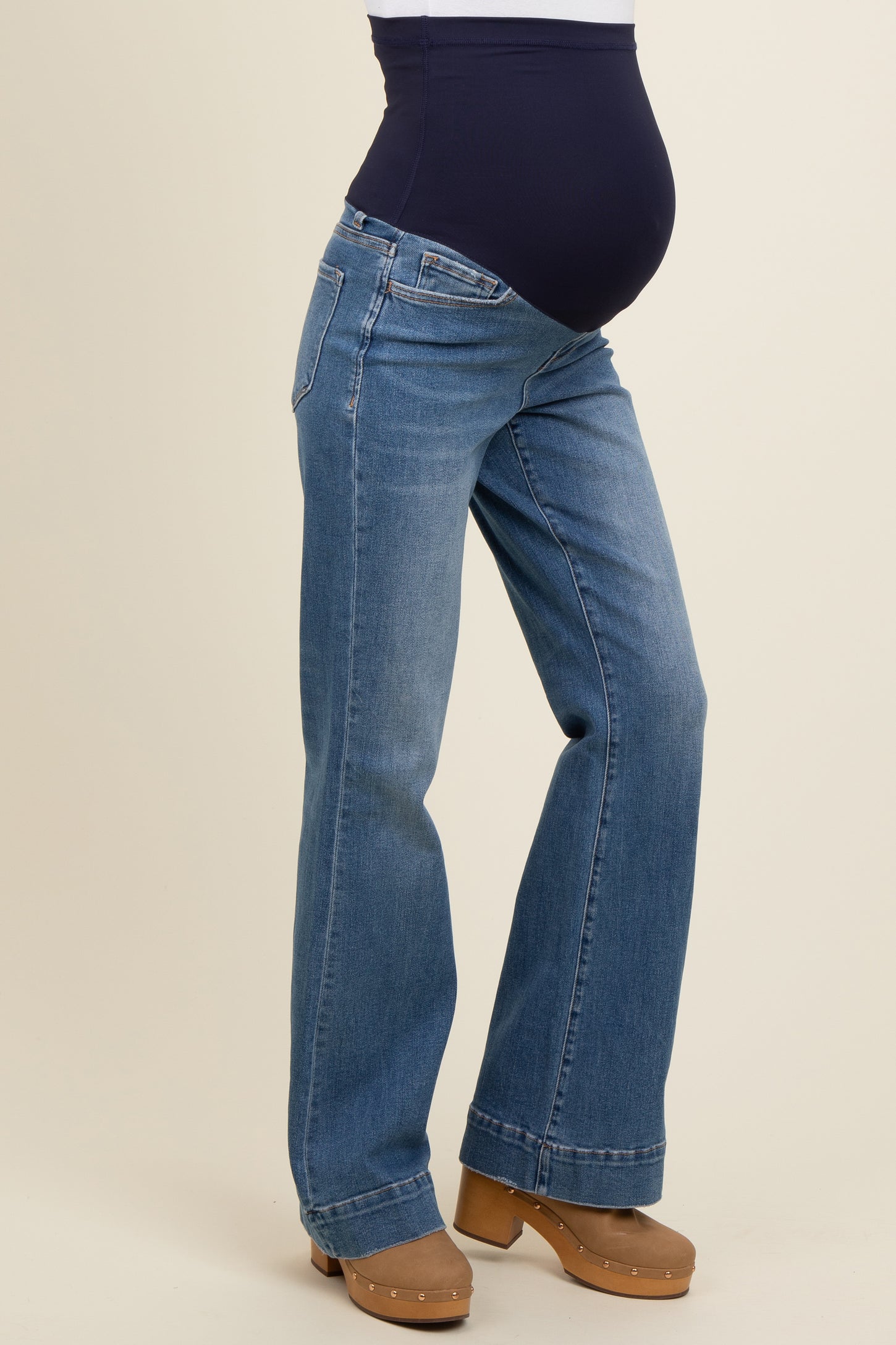 woman wearing blue maternity jeans with a wide waistband and visible baby bump