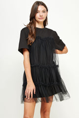 woman wearing a black short sleeve dress with tulle overlay and ruched detailing
