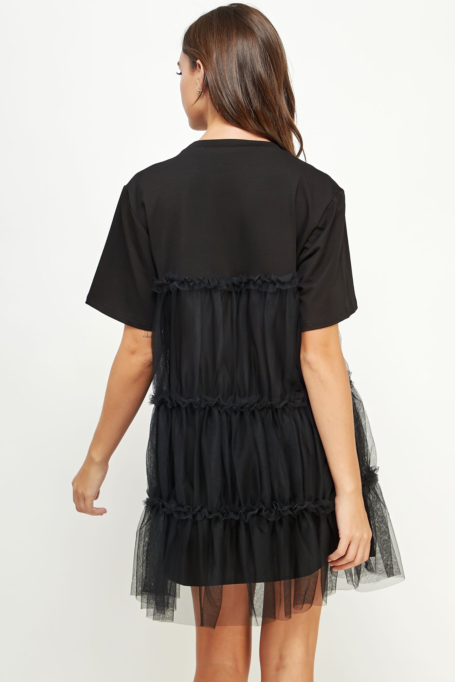 woman wearing a black t-shirt dress with a layered tulle ruffle design at the back